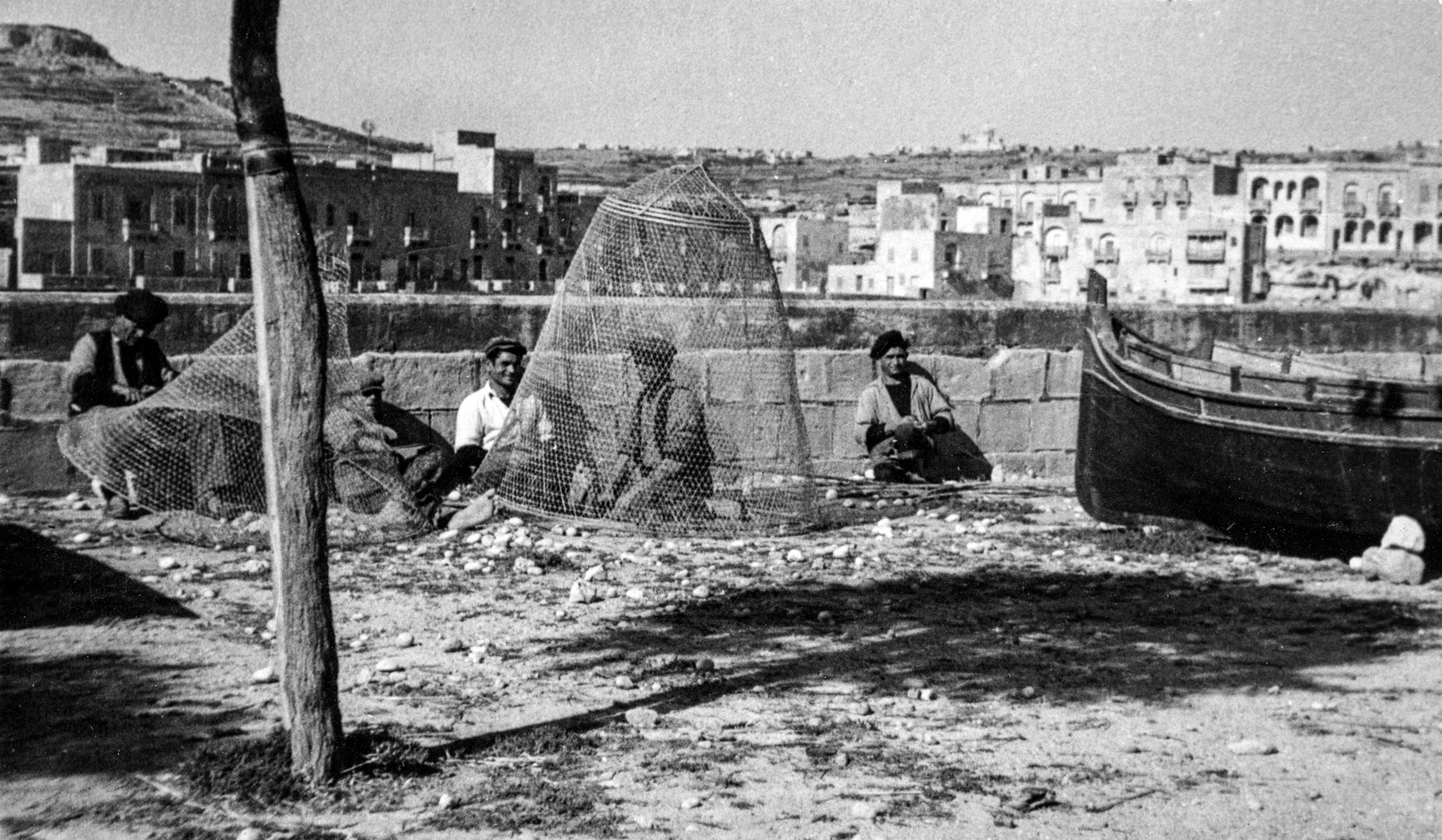 Fishermen resting near their nets, in the Menqa area of Marsalforn, as captured by Geo Furst in the 1930s.