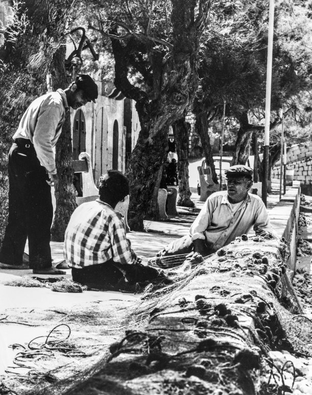 A group of fishermen discussing over their splayed fishing nets in Xlendi Bay, circa 1970, as captured by Gino Theuma.