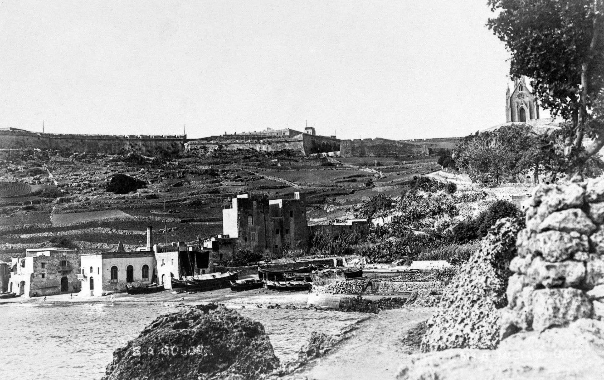 A view of Mgarr Harbour with Fort Chambray and our Lady of Lourdes chapel in the background, captured by EA Gouder, 1920.