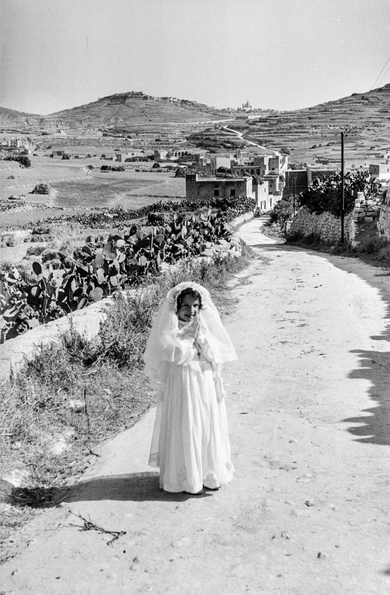 A girl in her Holy Communion dress on the road leading from Victoria to Zebbug, captured by Guido Stilon in 1964. Courtesy of Grace Cilia Vincenti & National Archives of Malta.
