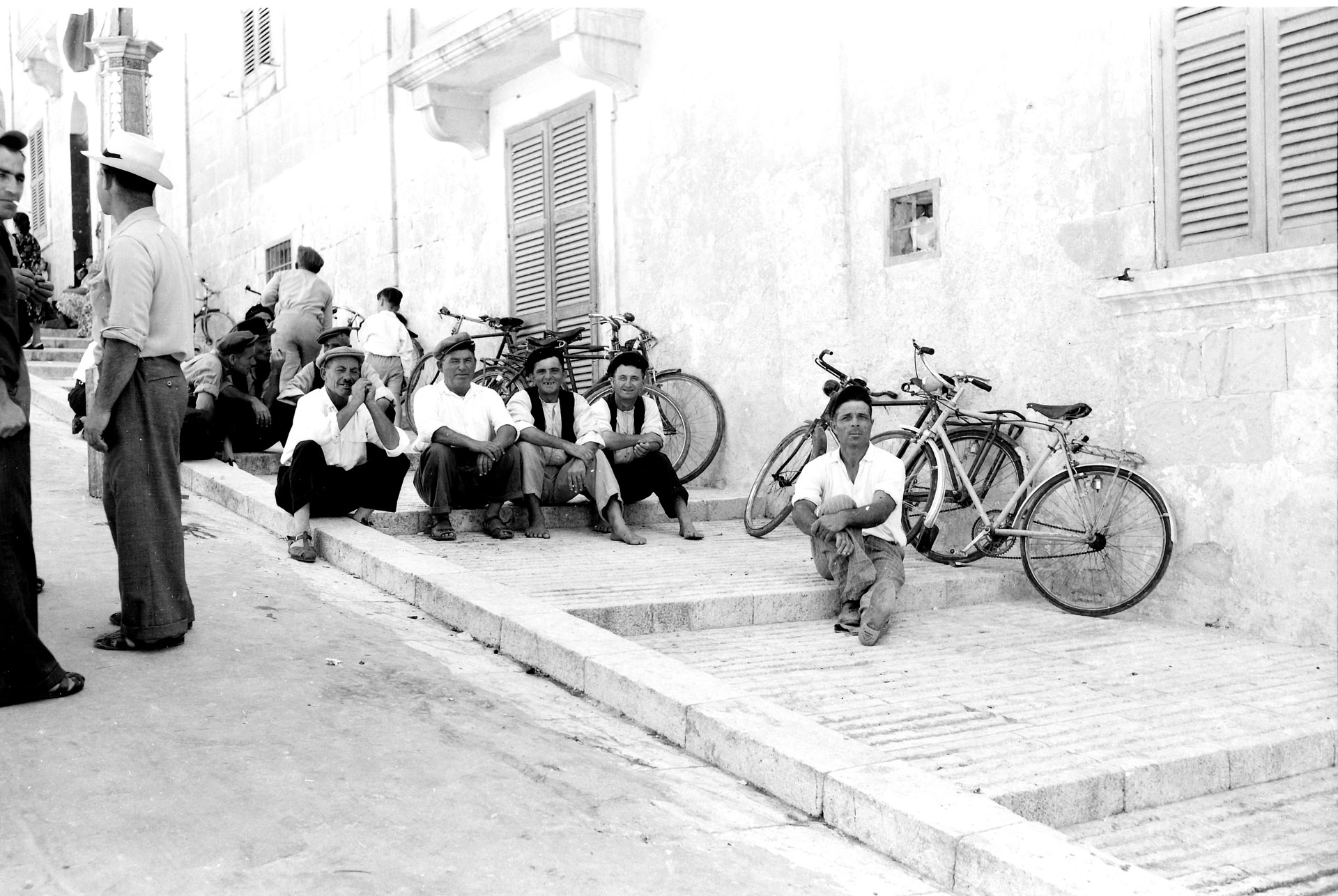 A group of friends sitting atop the steps leading up to the Citadel in Victoria, captured by Emmanuel Borg from Kalkara, 1960s.