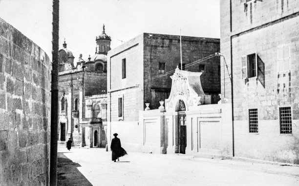 A member of the clergy greets passersby in front of the Seminary in Victoria, Gozo, circa 1950; photographer unknown.